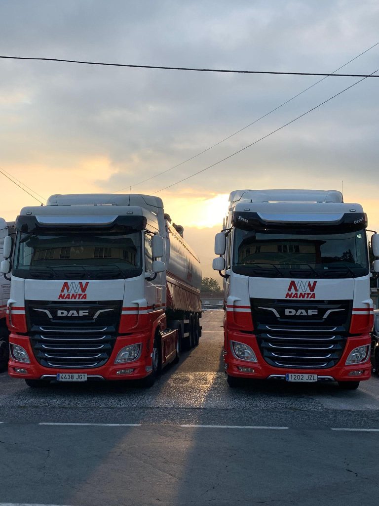 Dos camiones Nanta estacionados al amanecer, listos para transporte de mercancías.