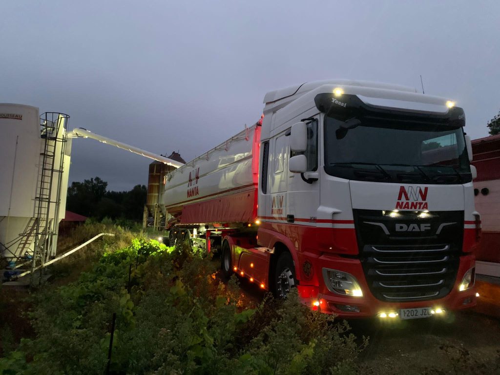 Camión Nanta descargando pienso en un silo agrícola durante la noche. Entrega de mercancías en silos.