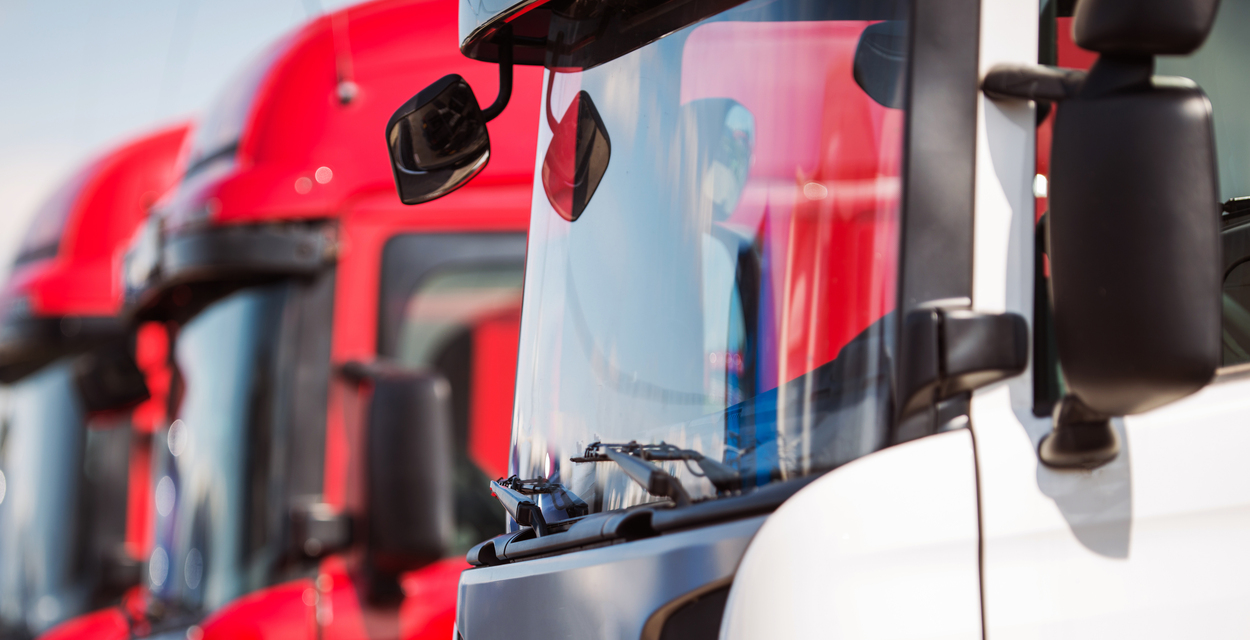 Cabinas de camiones de transporte en fila, una roja y otra blanca. Transporte de mercancías por carretera con flota moderna.